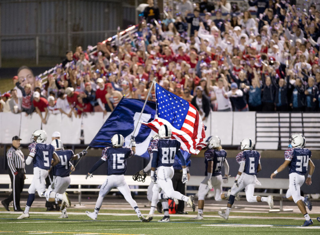 Parker Mellott (15) runs out on the field during senior night with the American flag. Sam Yu / Frederick News-Post.